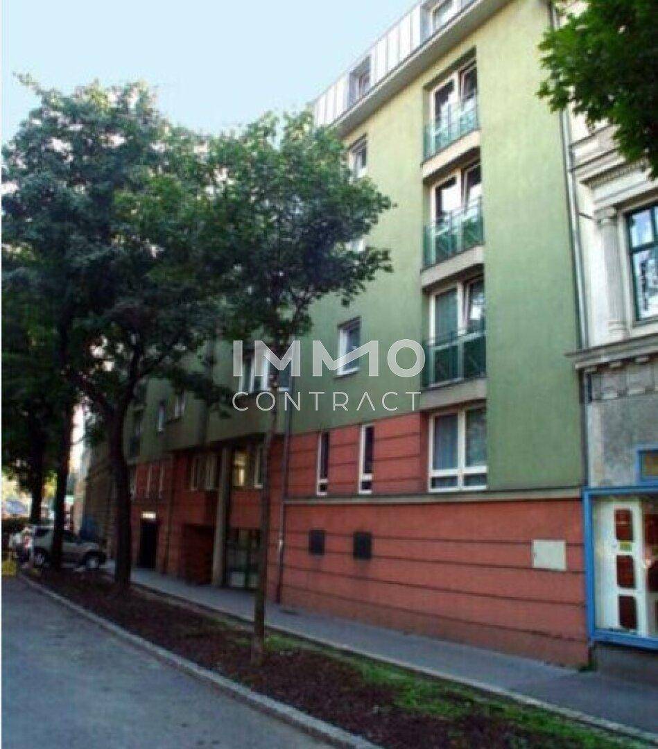 Mehrstöckiges Wohngebäude mit grüner Fassade und Balkonen an einer städtischen Straße.