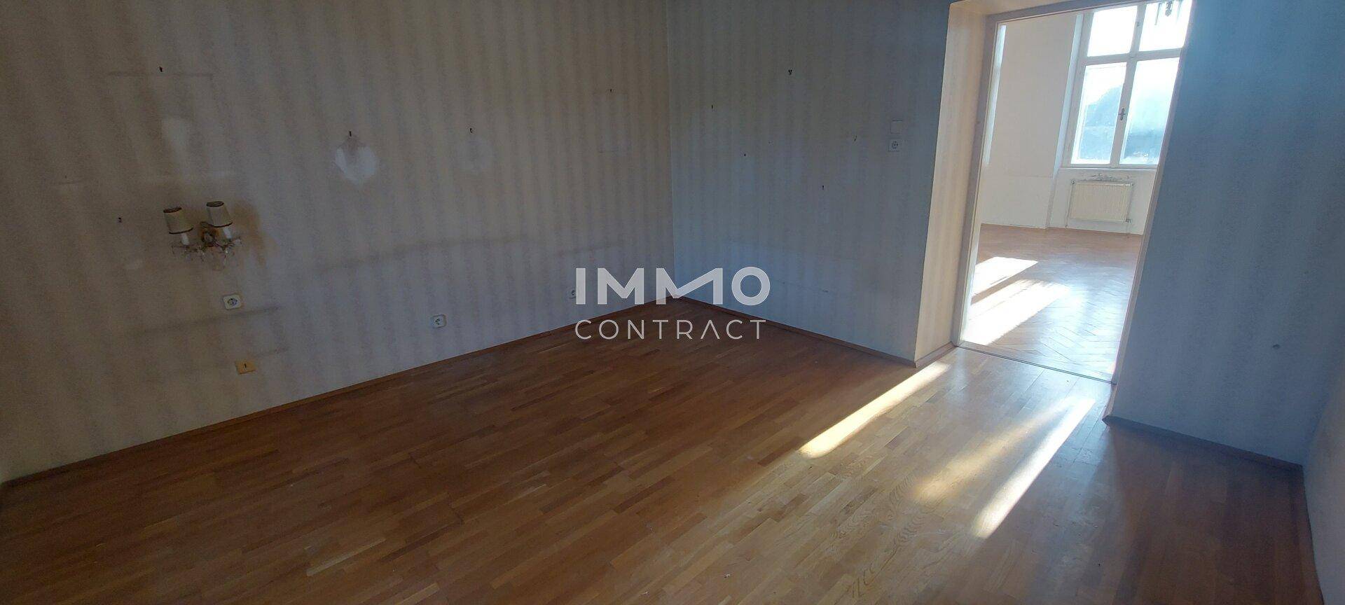 Leeres Zimmer mit Parkettboden und Tapeten, das Potenzial für eine moderne Umgestaltung bietet.