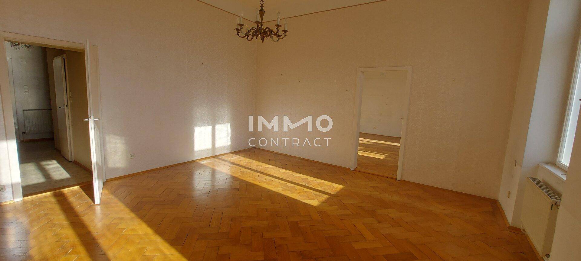 Helles Zimmer mit Fischgrätparkett und viel Tageslicht, das auf eine Renovierung wartet.