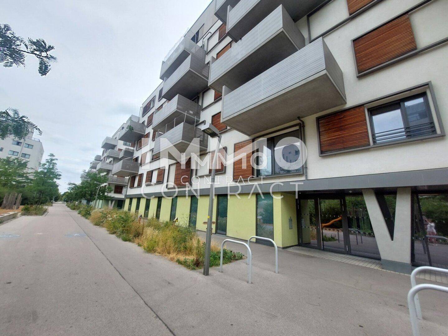 Moderne Wohngebäude mit Balkonen und Grünflächen entlang eines Fußwegs.