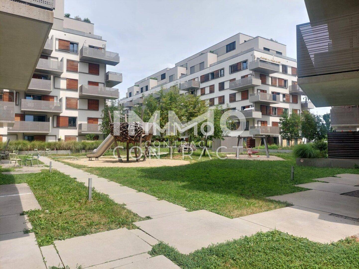 Moderner Kinderspielplatz mit Rutsche und Grünflächen zwischen Wohngebäuden.