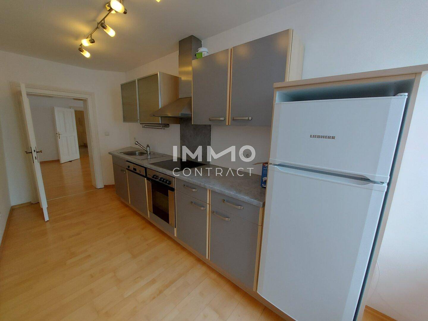 Funktionale Küche mit grauen Schränken, Kühlschrank und Herd, ideal für den täglichen Gebrauch.