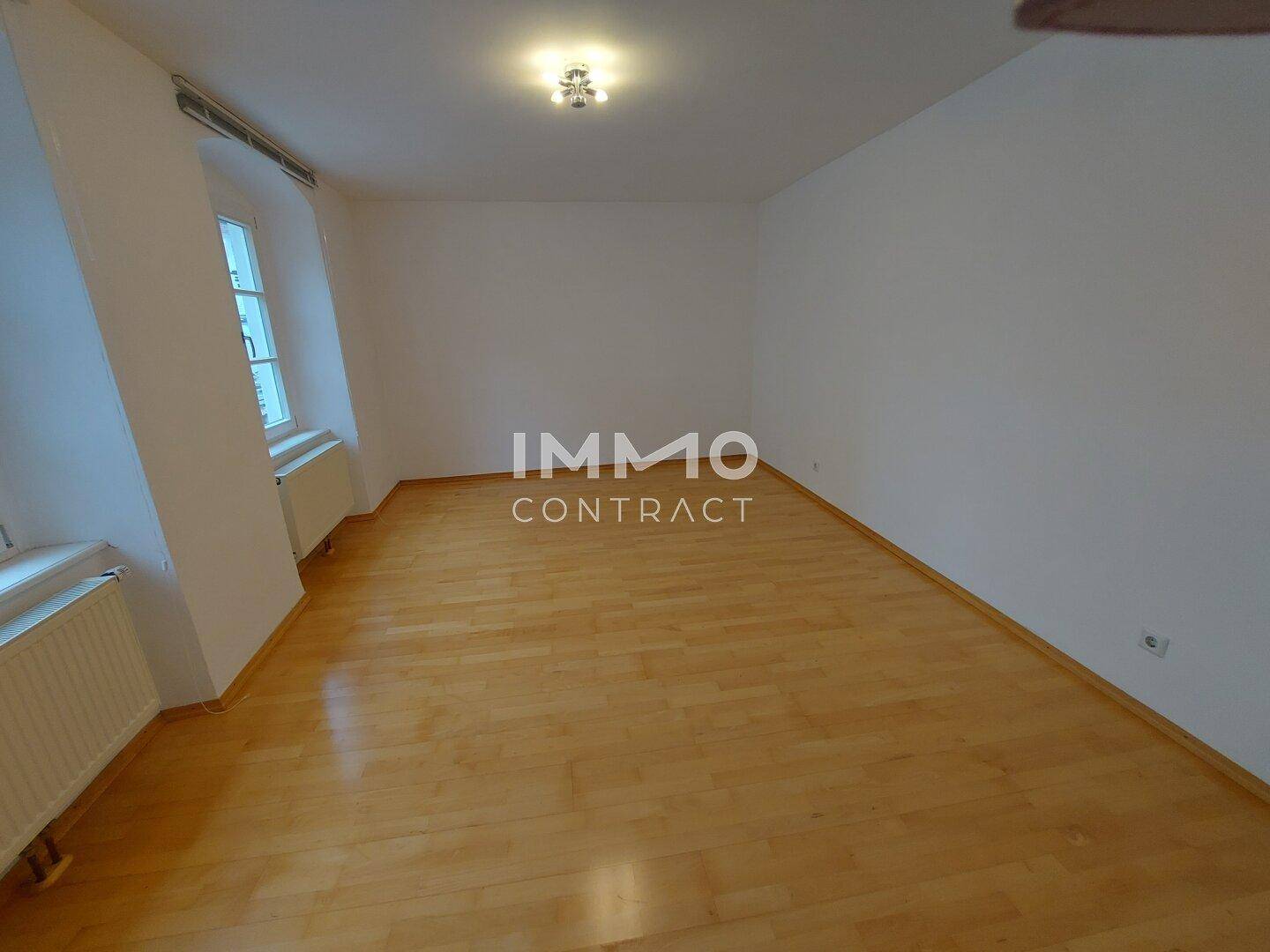 Geräumiges Zimmer mit Holzboden und zwei Fenstern, bietet viel Potenzial für neue Bewohner.