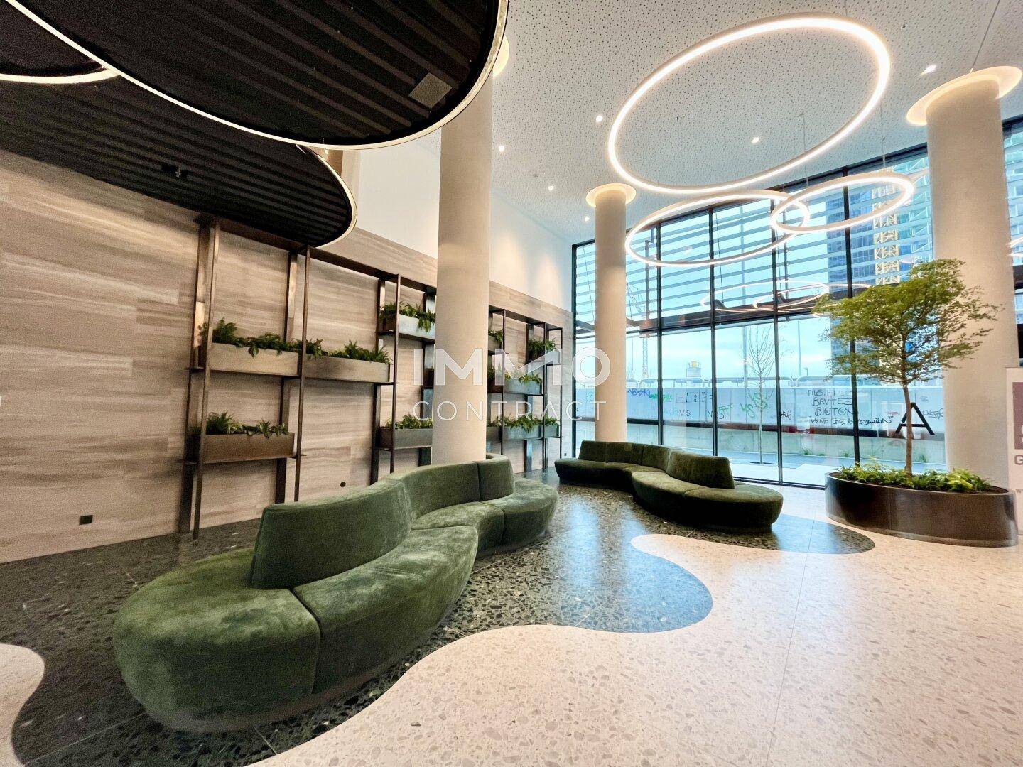 Elegante Lobby mit modernen Sitzgelegenheiten, hohen Decken und großen Fenstern.