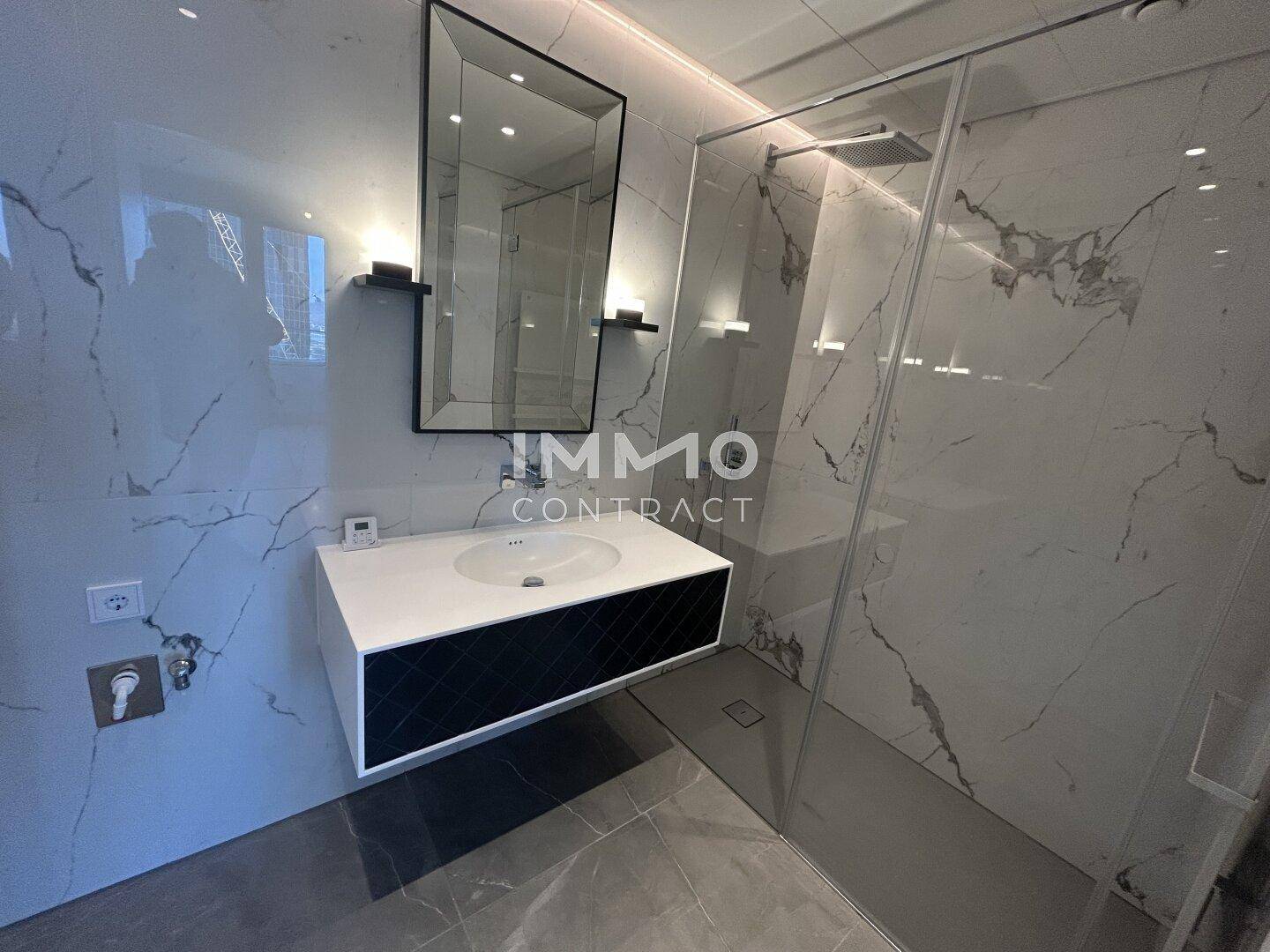 Modernes Badezimmer mit Marmorfliesen, Einzelwaschbecken und begehbarer Dusche.