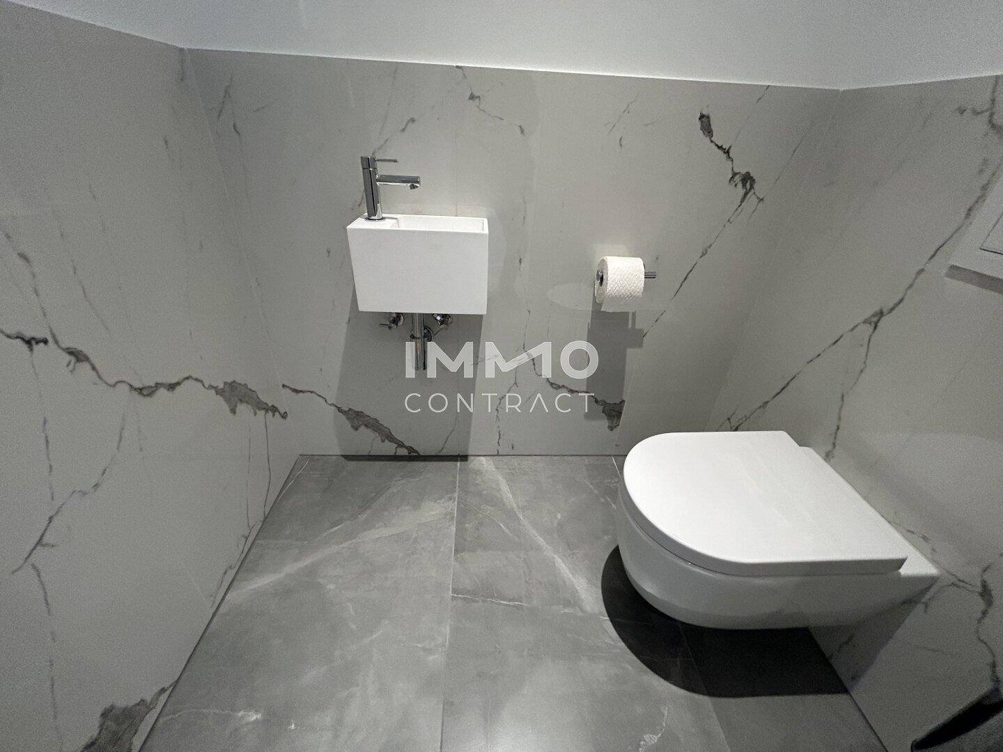 Modernes Gäste-WC mit Wand-WC, kleinem Waschbecken und Marmorfliesen.