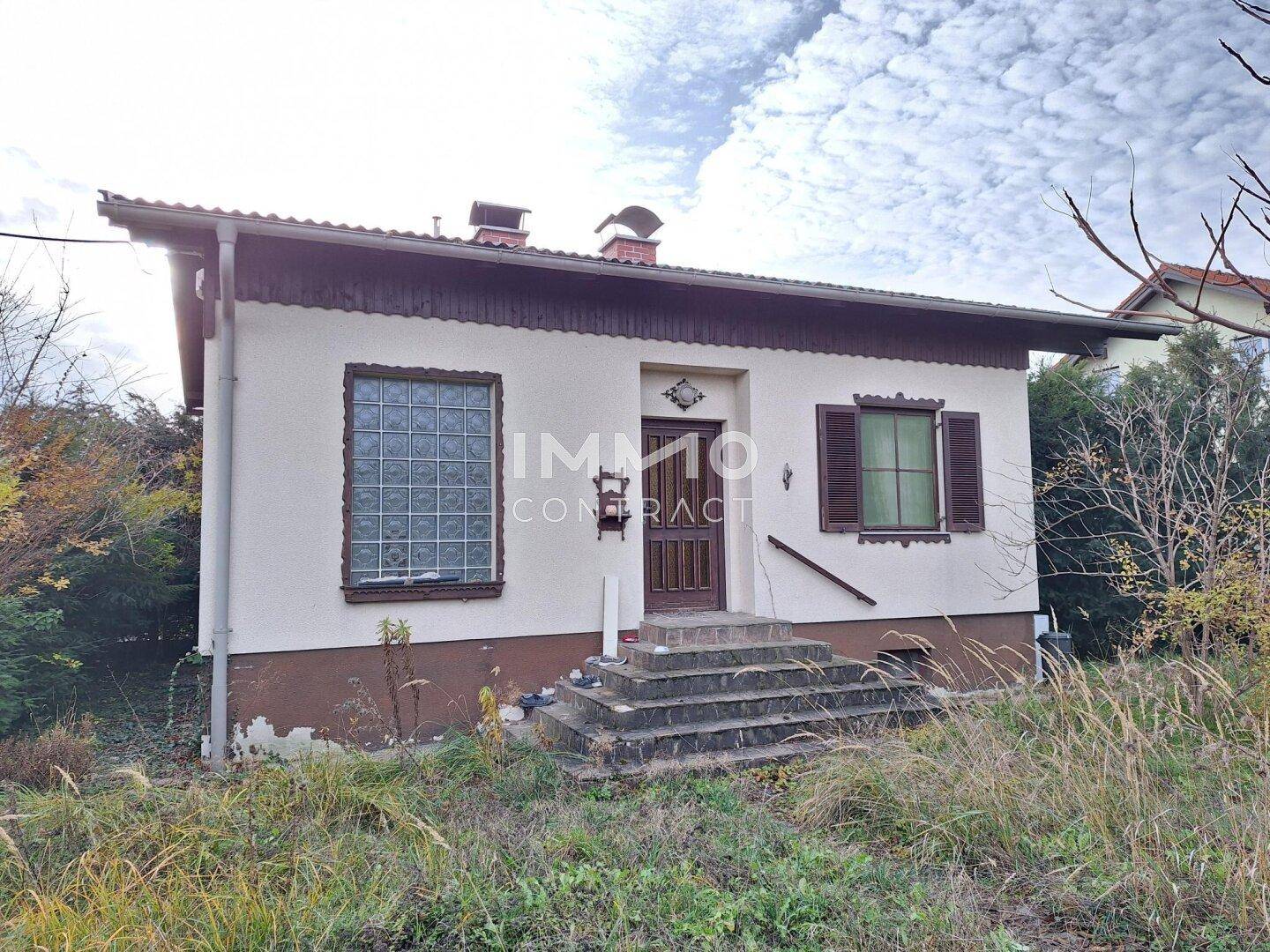 Kleines Einfamilienhaus mit einfacher Fassade und Treppenzugang in ländlicher Umgebung.