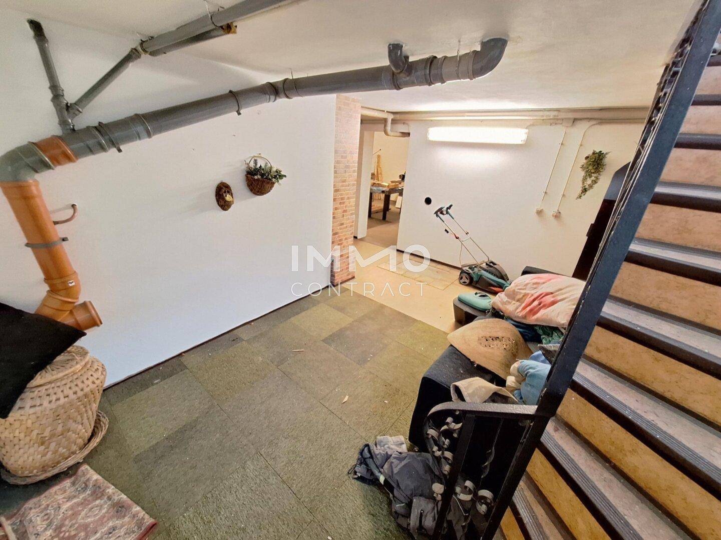 Kellerbereich mit sichtbaren Rohren, Teppichboden und Treppenzugang.