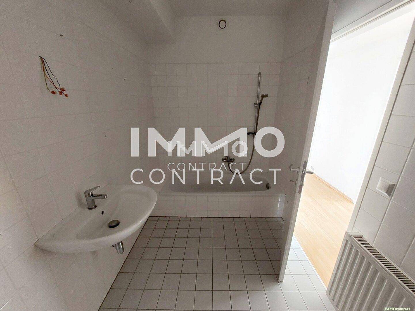 Einfaches Badezimmer mit Badewanne, Waschbecken und weißen Wand- und Bodenfliesen.