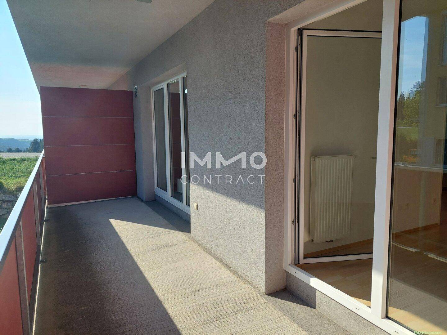 Geräumiger Balkon mit Betonboden und Blick ins Grüne, zugänglich vom Innenbereich.