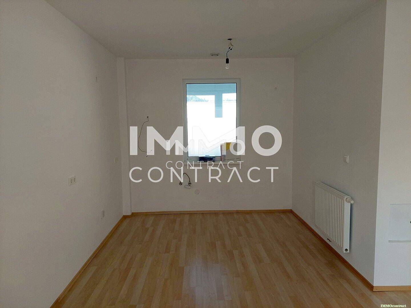 Unmöblierter Raum mit hellem Laminatboden und Fenster, bereit zur individuellen Gestaltung.