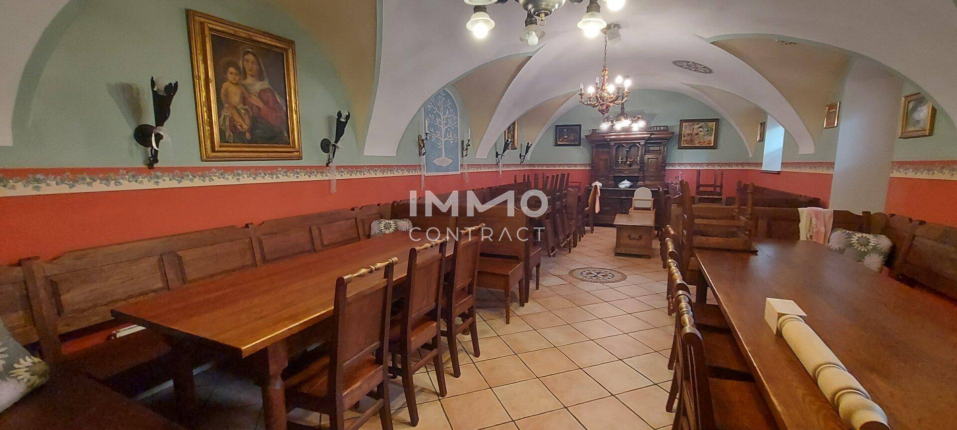 Geräumiger Speisesaal mit rustikalen Holzmöbeln, Gewölbedecken und traditioneller Wanddekoration, bereit für Gäste.