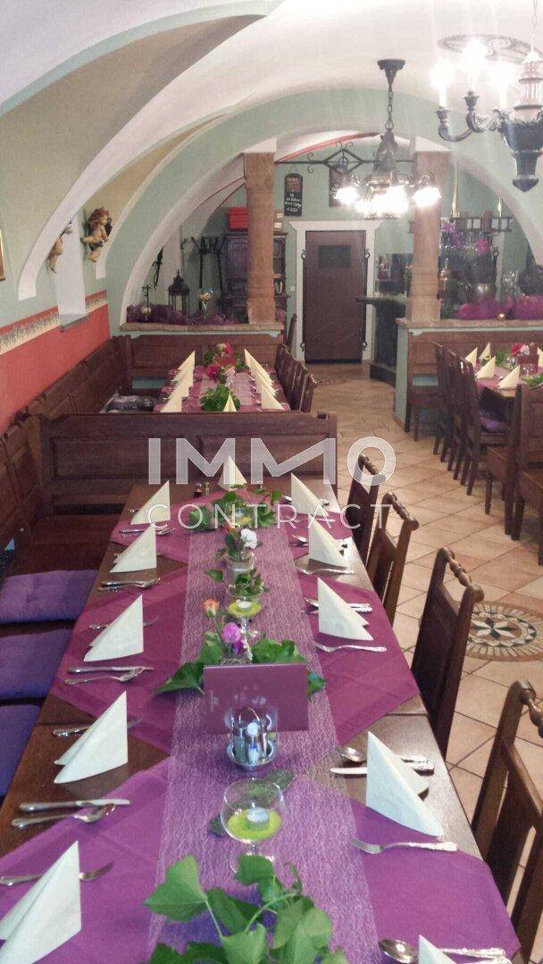 Ein festlich gedeckter Tisch in einem traditionellen Speisesaal mit lila Tischläufern und Servietten, bereit für eine Feier.