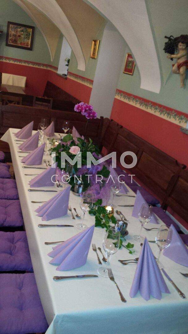 Ein festlich dekorierter Tisch mit lila Servietten und Blumenarrangements in einem traditionellen Ambiente.