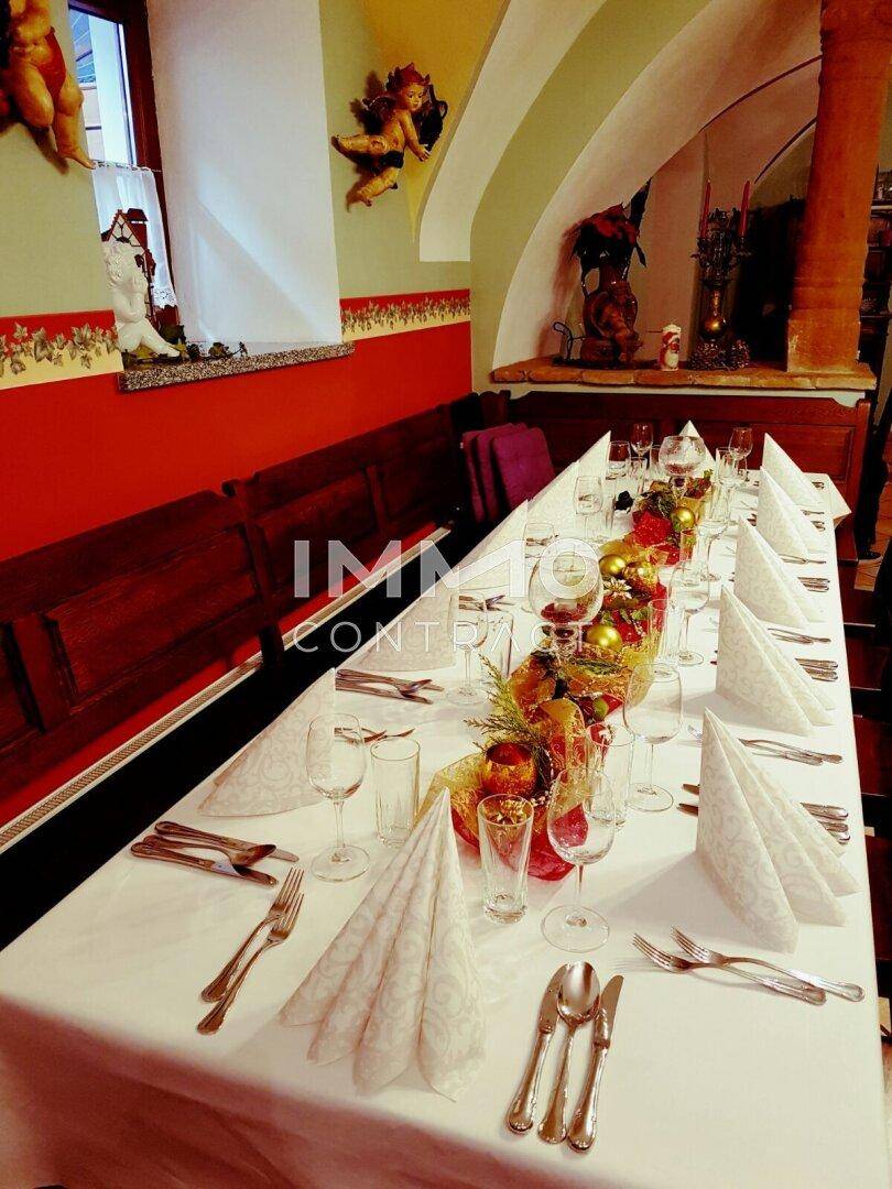 Ein elegant gedeckter Tisch mit weißer Tischdecke, Gläsern und Besteck, bereit für eine festliche Mahlzeit.