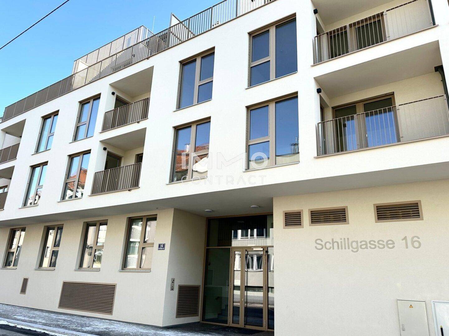 Moderne Fassade eines Wohngebäudes mit Balkonen, großen Fenstern und dem Eingangsbereich.