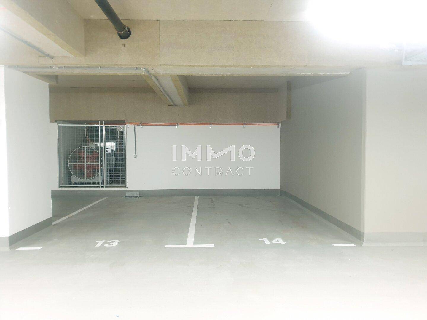 Leere Parkplätze in der Tiefgarage mit klaren Markierungen und Belüftungsanlage.