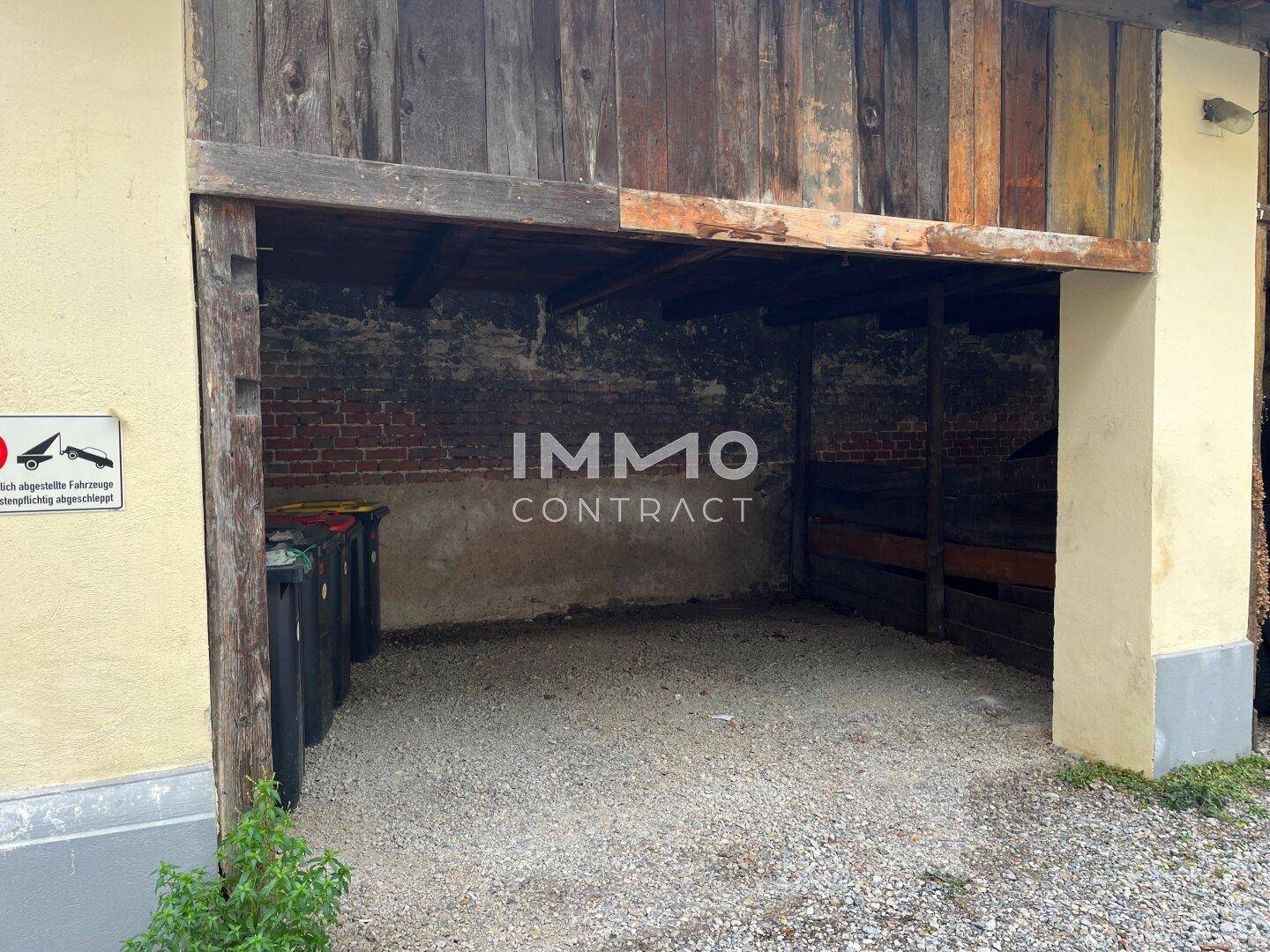 Rustikaler offener Unterstand mit Kiesboden, ideal als Garage oder Abstellfläche.