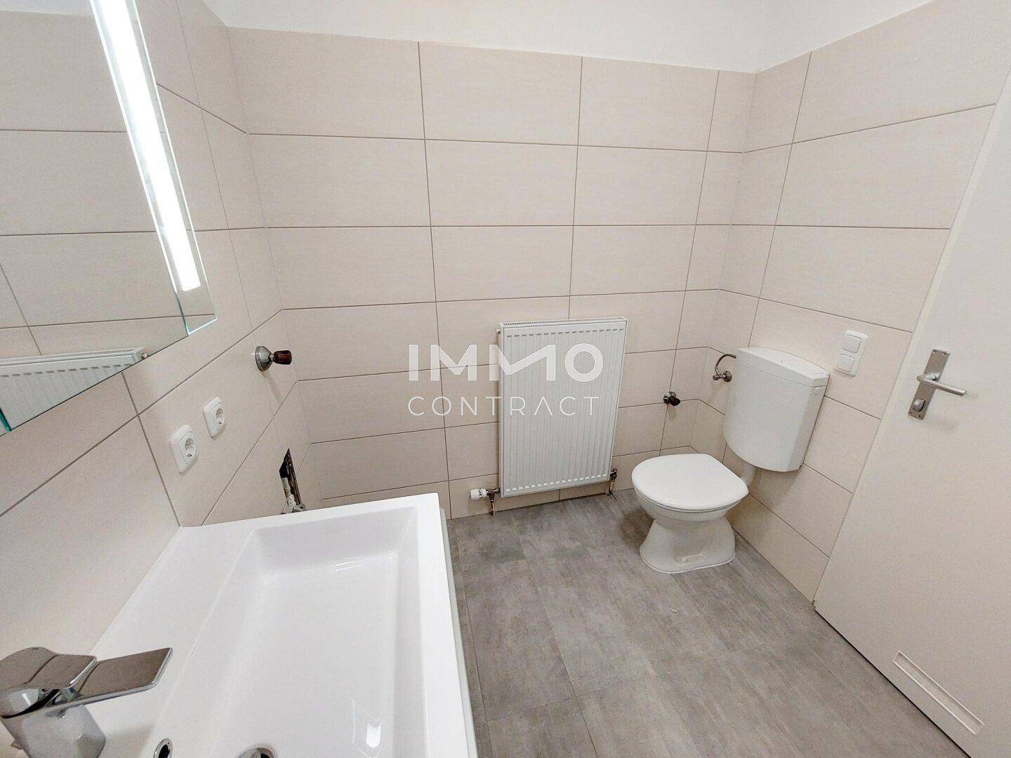 Modernes WC mit beigefarbenen Fliesen, wandmontiertem Heizkörper und Einzelwaschbecken.