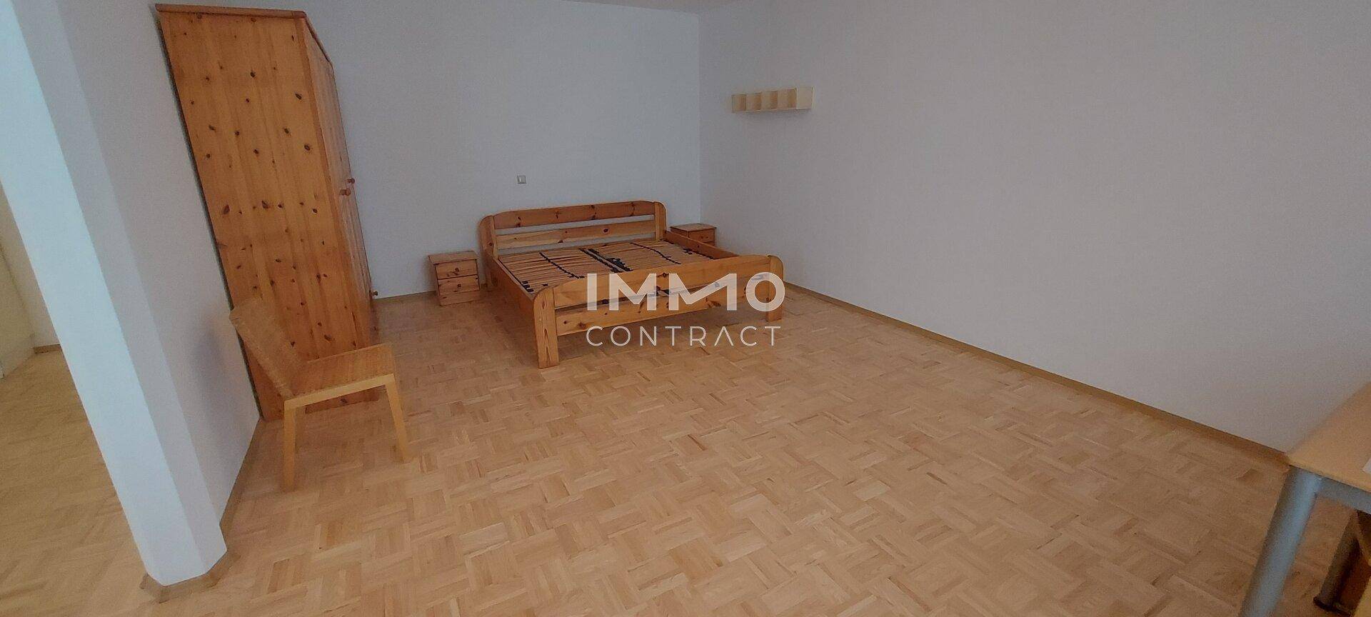 Schlafzimmer mit Holzbett, Nachttischen und einem Kleiderschrank, ausgestattet mit Parkettboden.