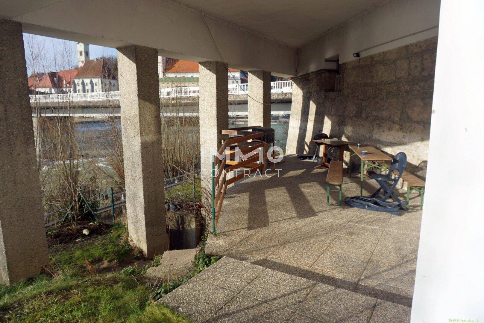 Überdachter Außenbereich mit Sitzgelegenheiten und direktem Blick auf den Fluss und die Umgebung.