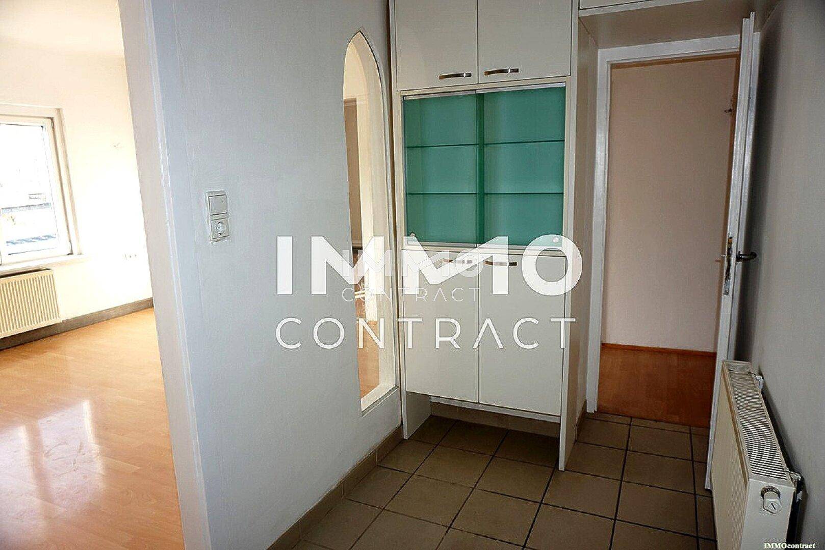 Eingangsbereich mit Fliesenboden, Einbauschrank und Blick in angrenzende Räume mit Heizkörper.