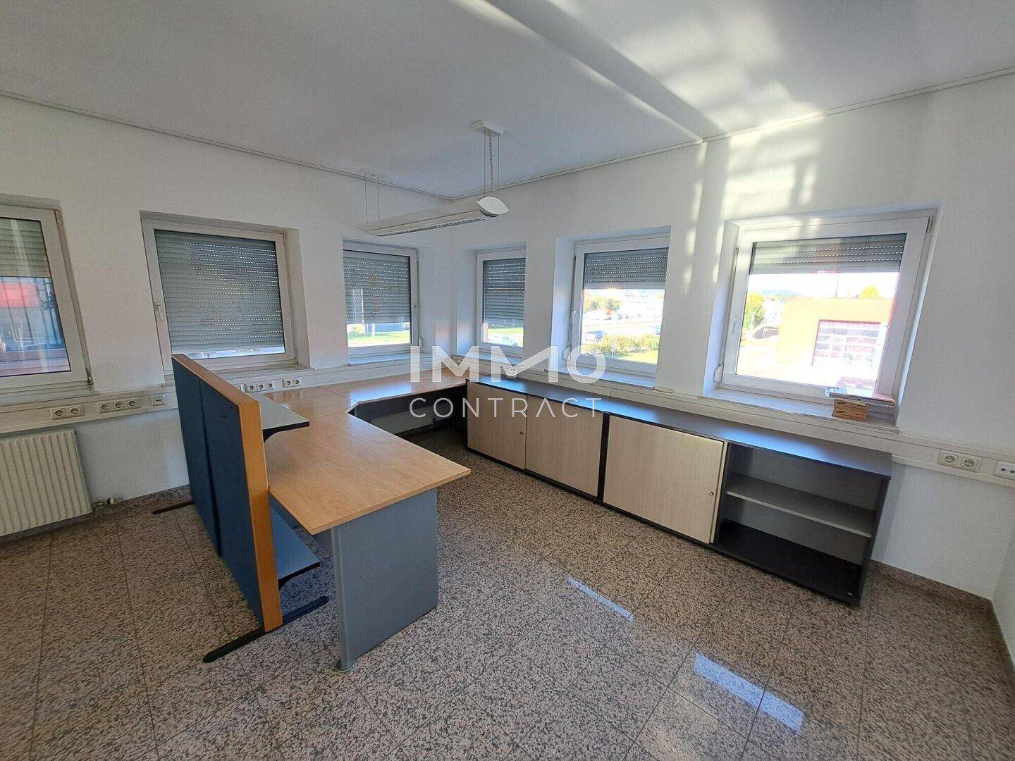 Geräumiges Büro mit Schreibtisch, Stauraum und Fenstern mit Blick nach draußen.
