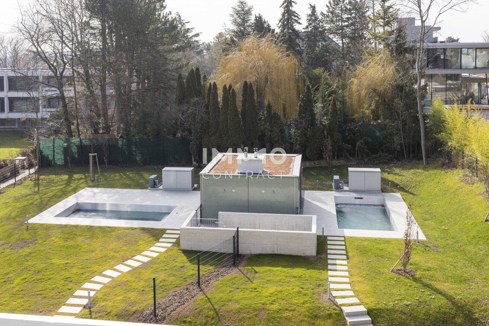 Außenansicht des Gebäudes mit zwei Pools und gepflegter Grünfläche.