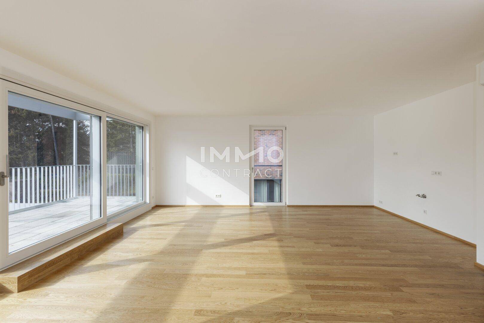 Geräumiges Wohnzimmer mit Parkettboden und viel Tageslicht durch große Fenster.