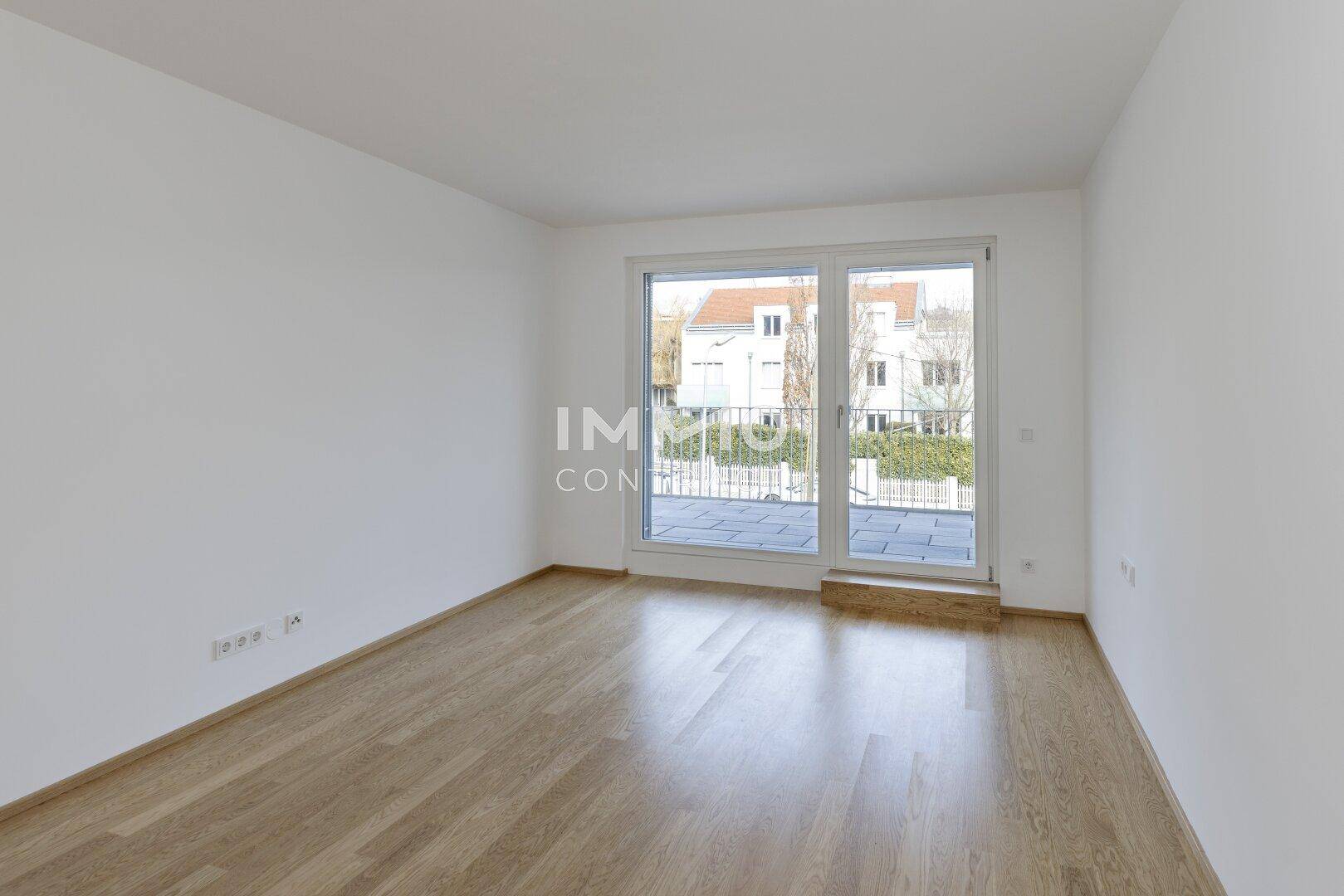 Schlafzimmer mit Holzboden und direktem Zugang zu einem Balkon oder einer Terrasse.