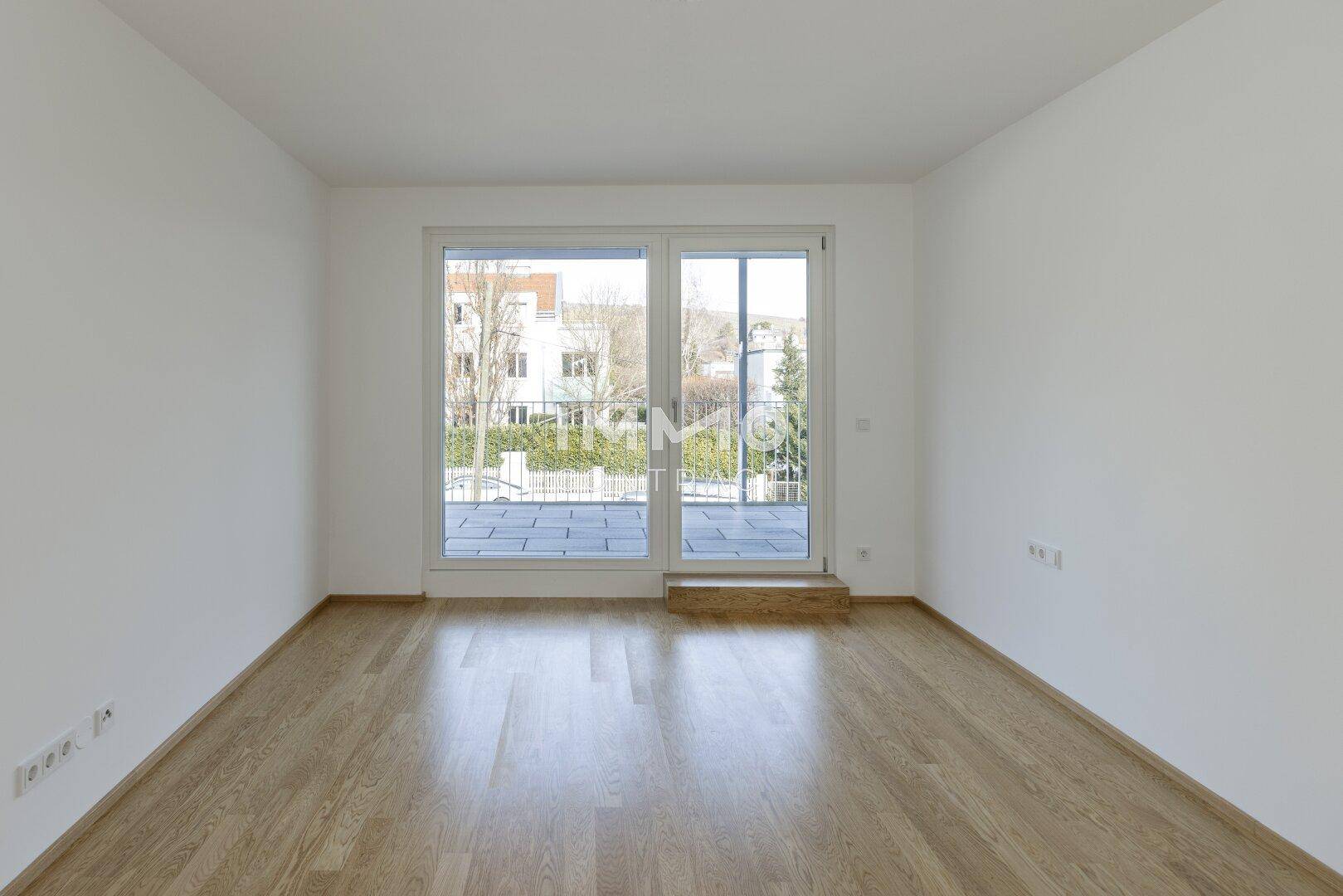 Helles Schlafzimmer mit Parkettboden und großem Fenster mit Blick nach draußen.