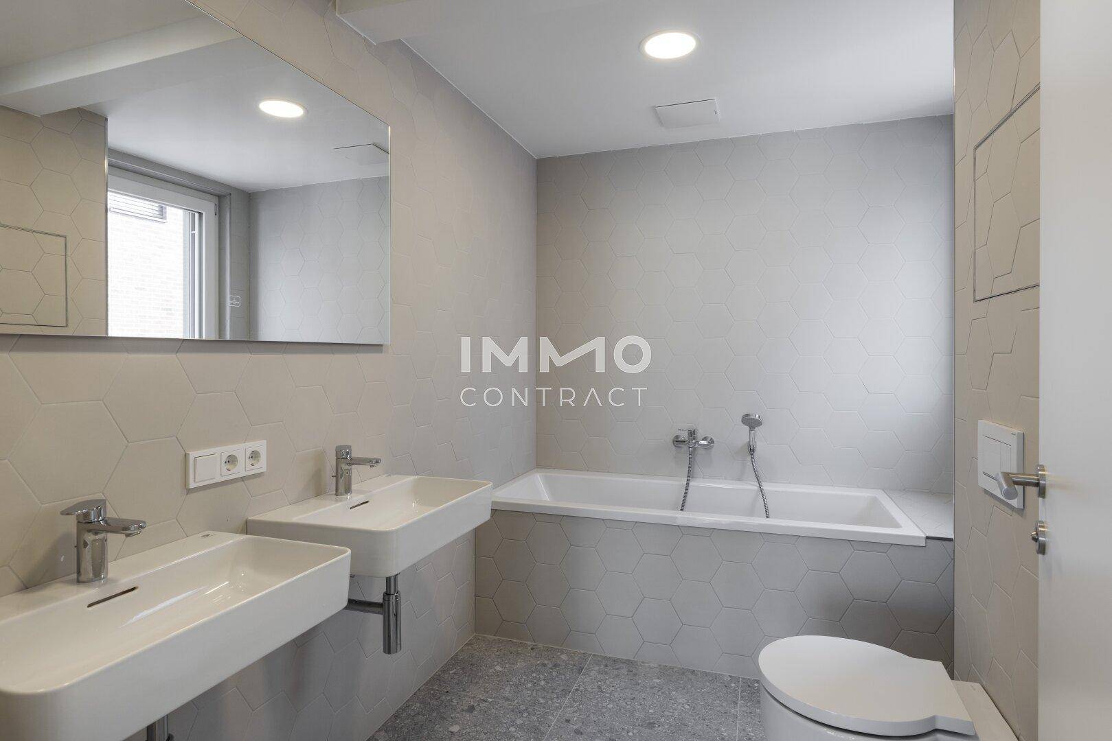Modernes Badezimmer mit Doppelwaschbecken, Badewanne und sechseckigen Fliesen.