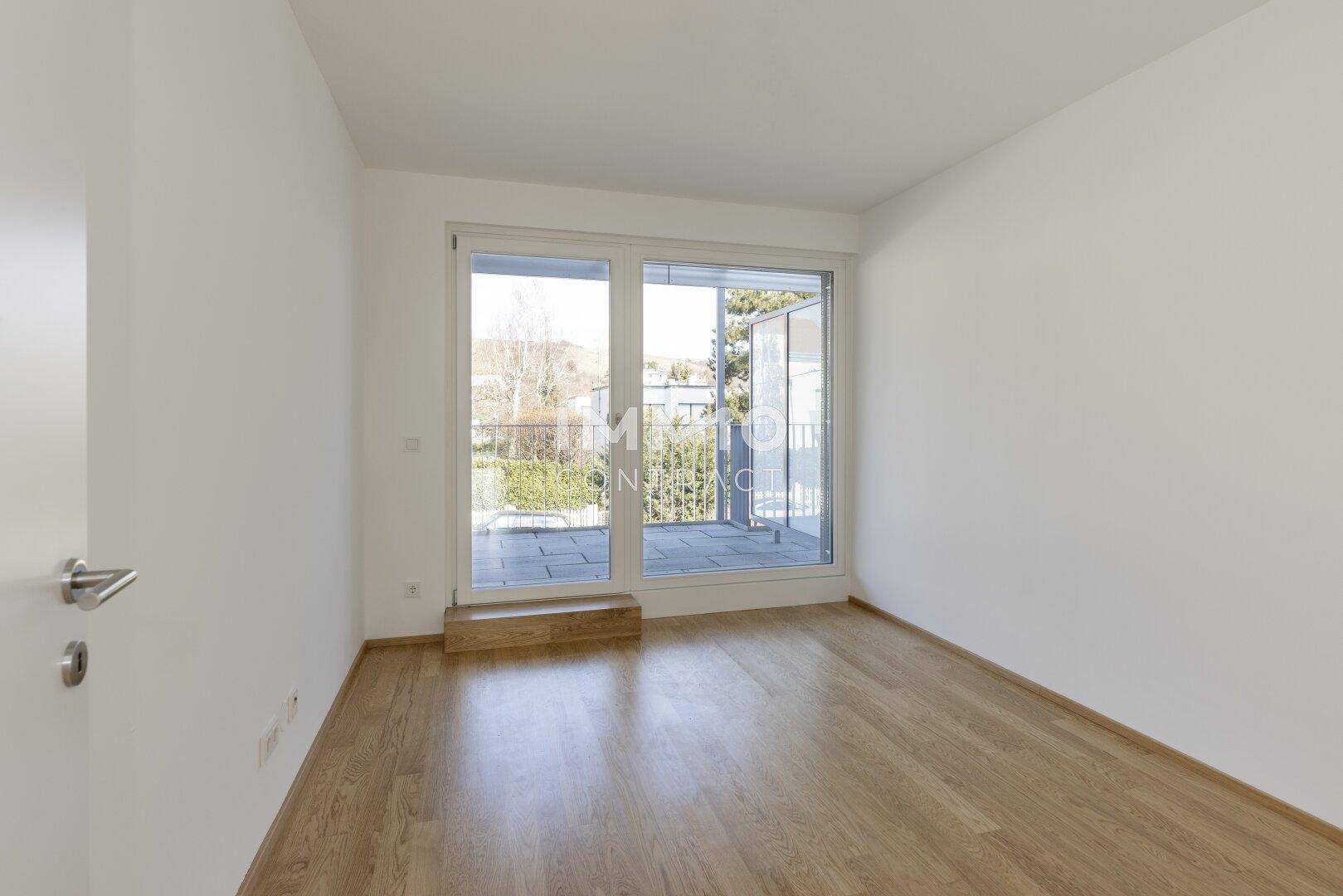 Geräumiges Schlafzimmer mit Holzboden und Zugang zu einem kleinen Balkon.