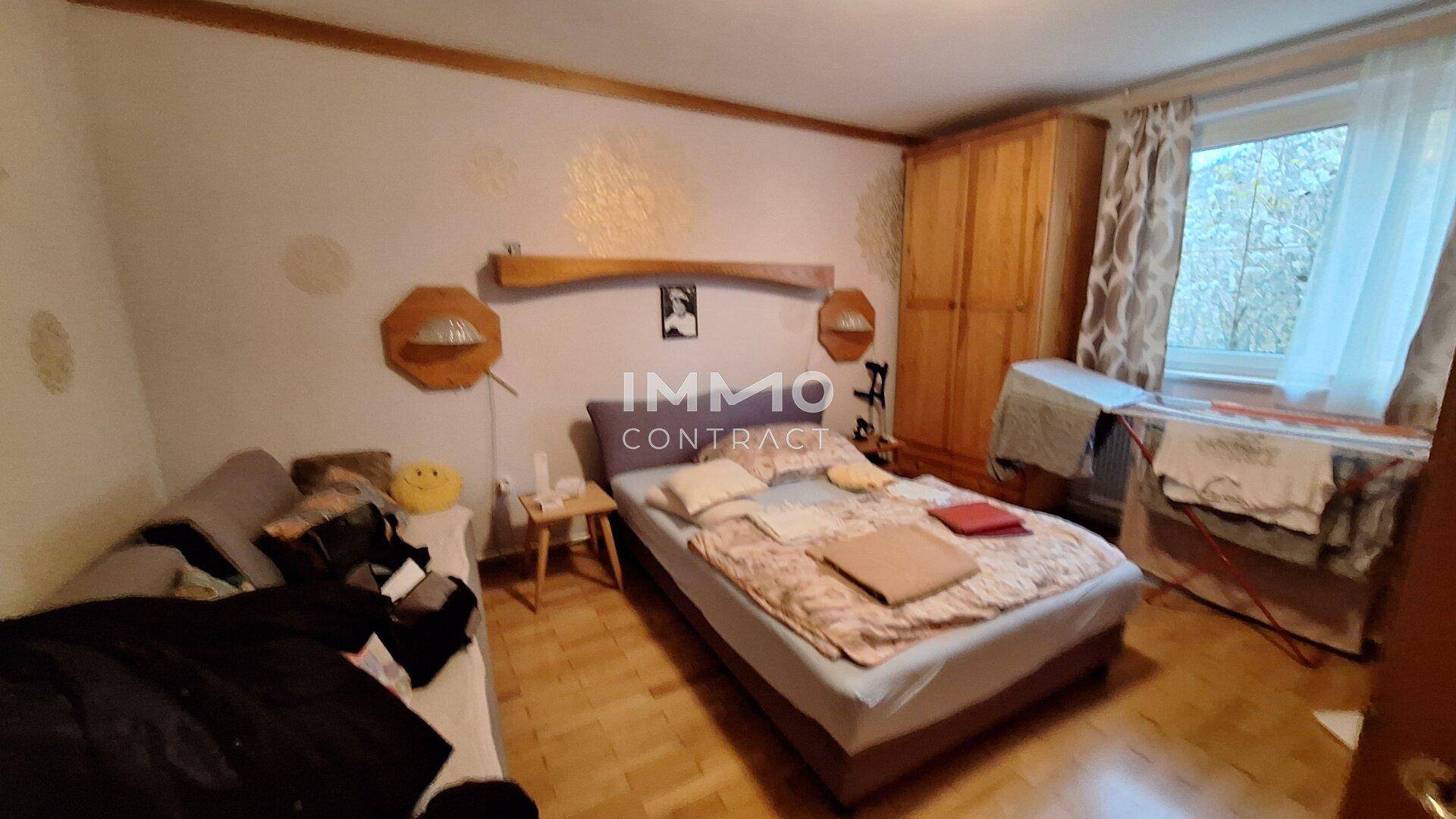 Gemütliches Schlafzimmer mit Holzboden, Doppelbett und einem Fenster, das Tageslicht hereinlässt.