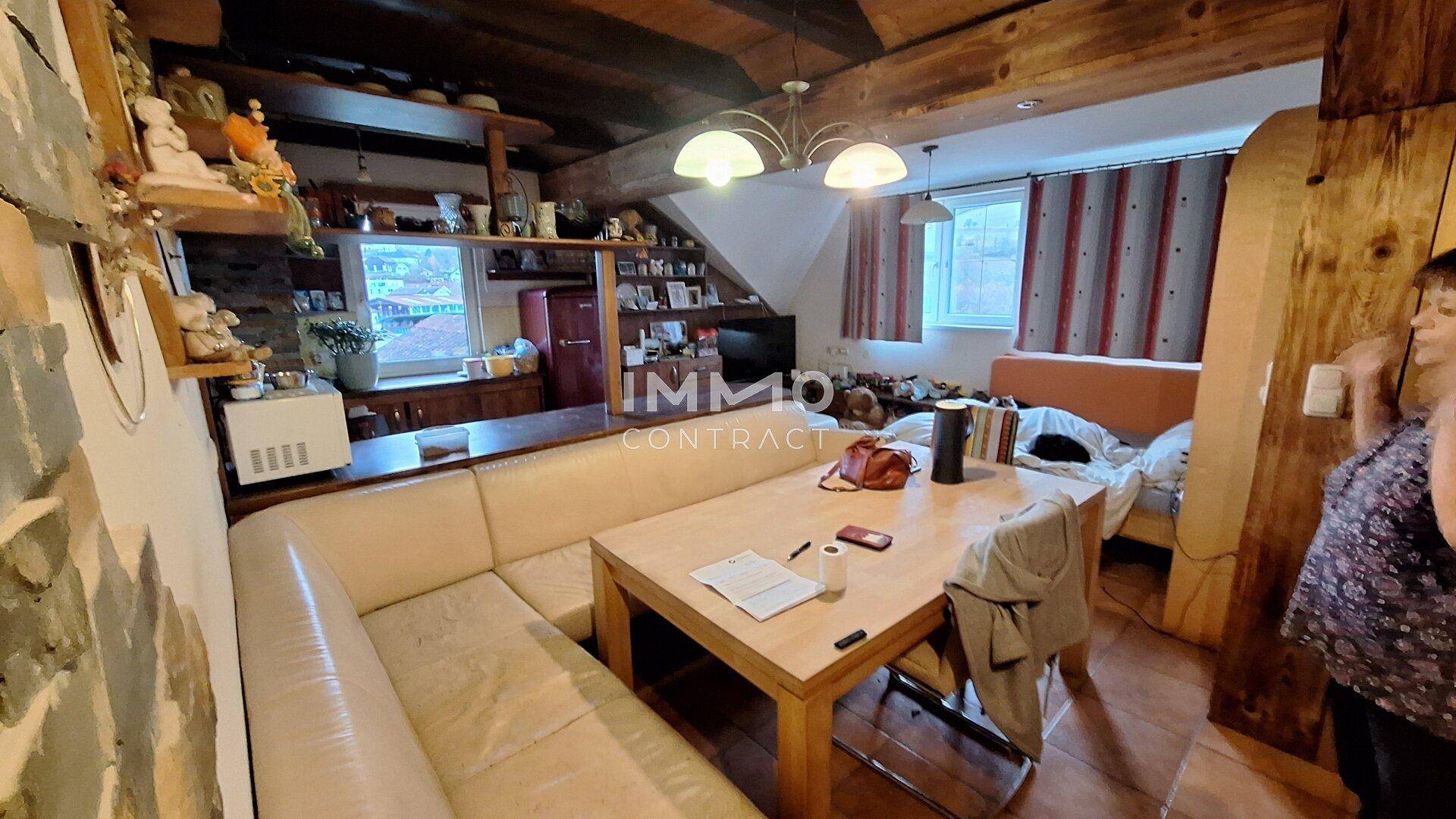Rustikaler Wohn-Essbereich im Dachgeschoss mit Holzbalken und gemütlicher Sitzecke.