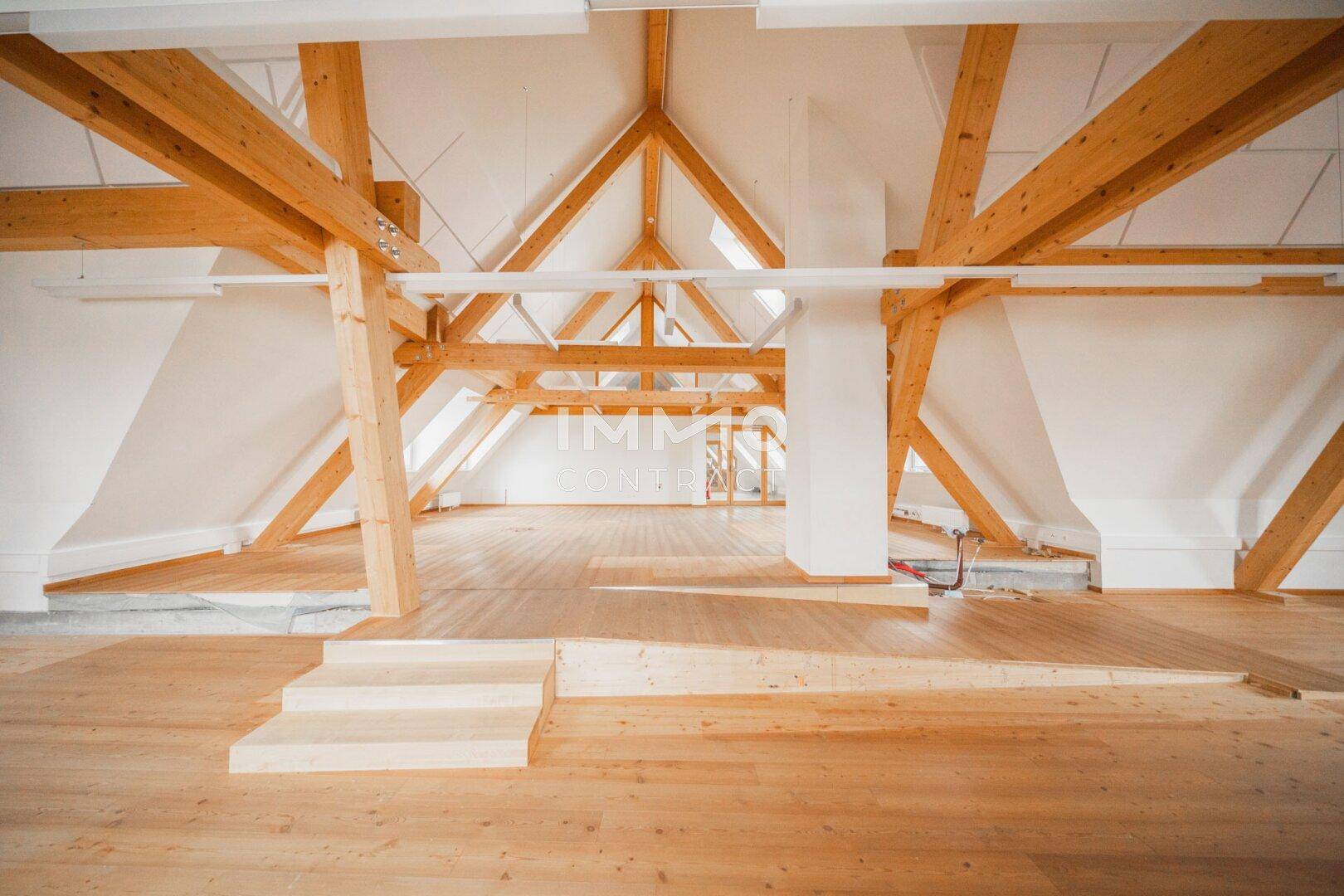 Heller Dachbodenraum mit markanten Holzbalken und schrägen Wänden, bietet vielseitige Gestaltungsmöglichkeiten.