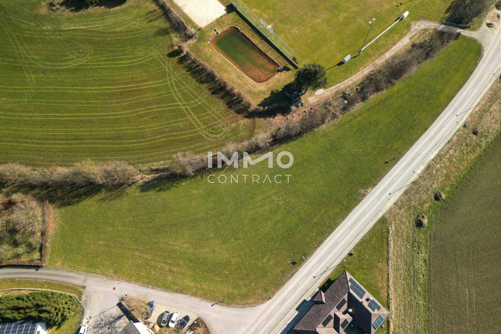 Übersichtliche Luftaufnahme des Grundstücks mit angrenzender Straße, Sportplatz und weiteren Gebäuden in der Umgebung.
