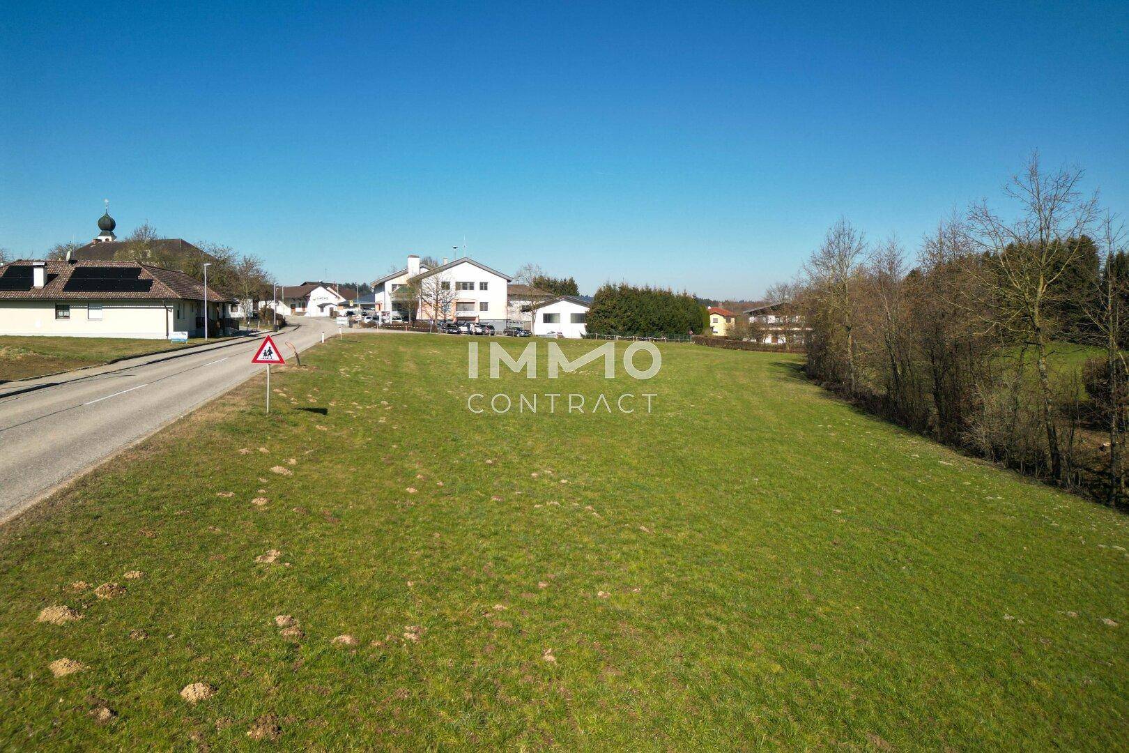 Weitläufiges grünes Grundstück mit Blick auf die umliegende Bebauung und Landschaft unter blauem Himmel.