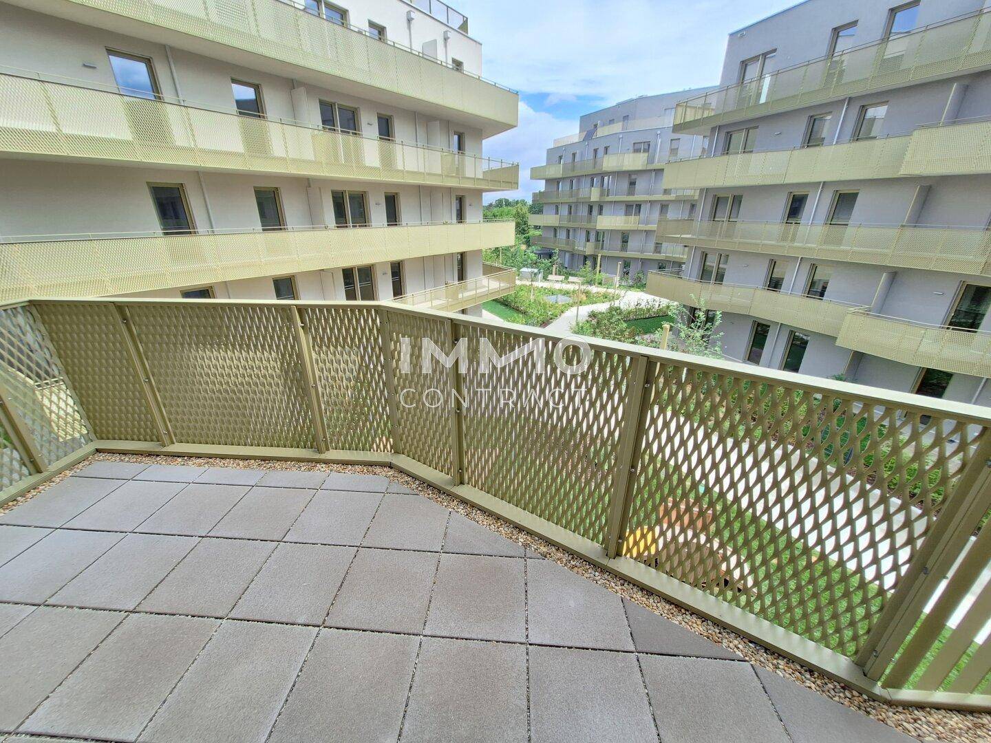 Balkon mit Gitterbrüstung und Blick auf moderne Wohngebäude und grüne Innenhöfe.
