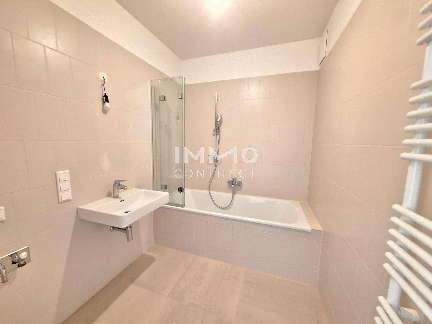 Modernes Badezimmer mit Badewanne, Duschwand, Einzelwaschbecken und Handtuchheizkörper.