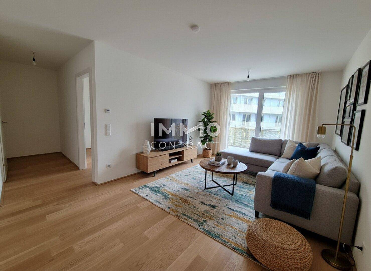 Gemütliches Wohnzimmer mit Sofa, Teppich und Holzboden, hell durch große Fenster.