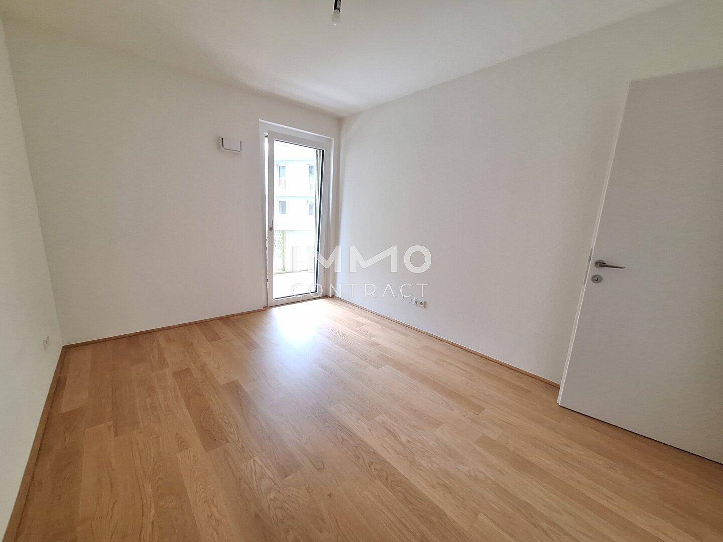 Heller, unmöblierter Raum mit Holzboden und Zugang zu einem Außenbereich.