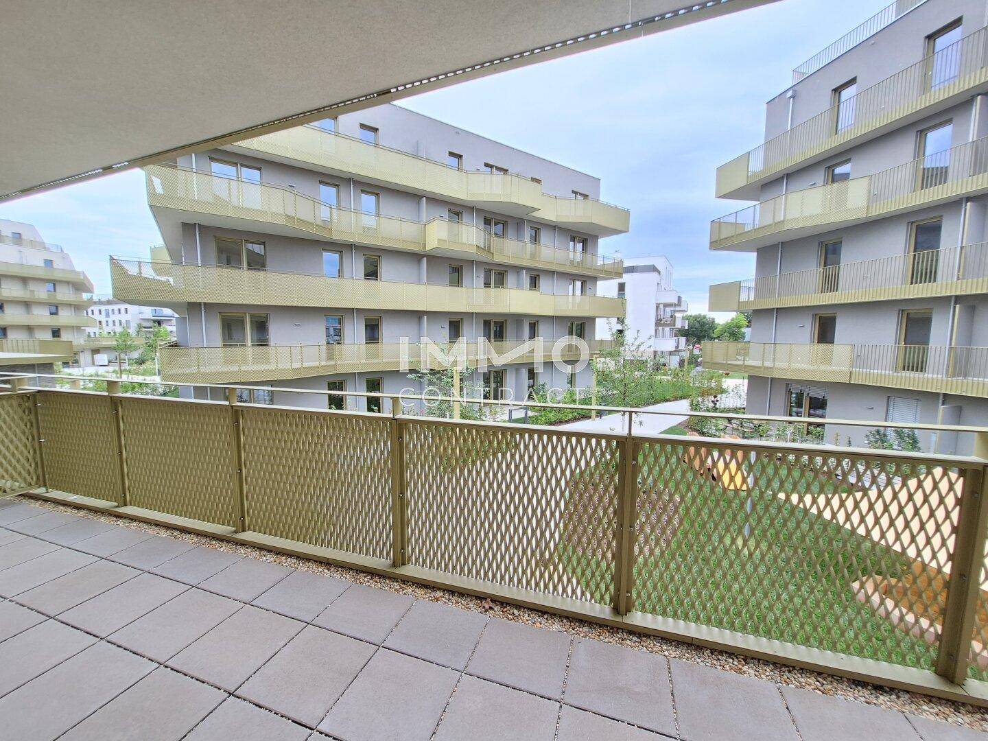 Großer Balkon mit Blick auf die moderne Wohnanlage und grüne Innenhöfe.