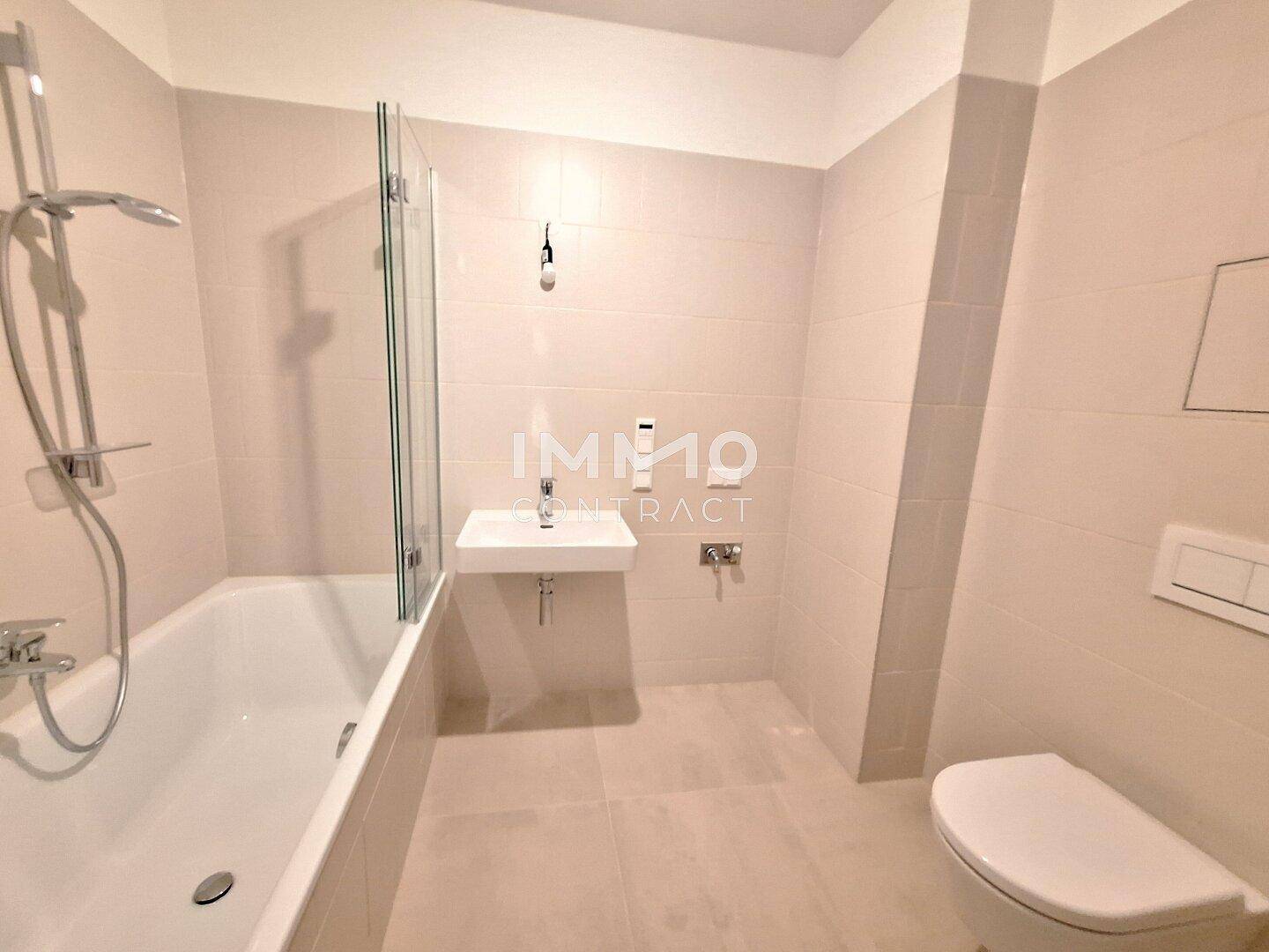 Modernes Badezimmer mit Badewanne, Dusche und Wand-WC in hellen Fliesen.