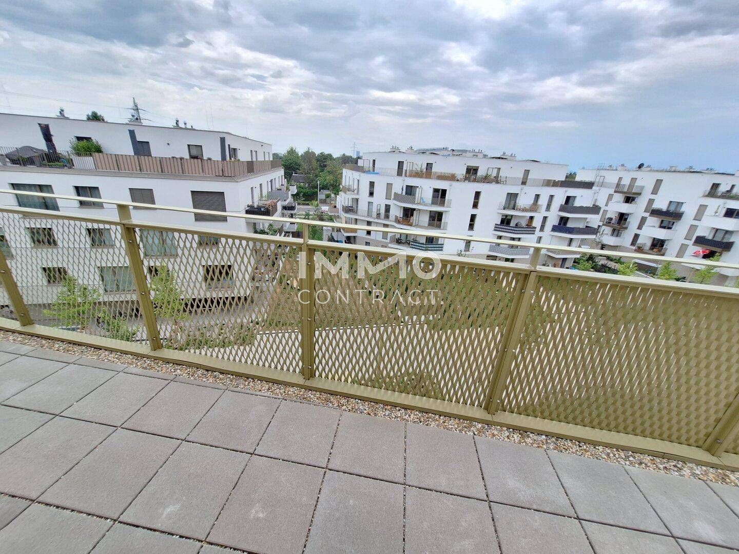 Balkon mit Blick auf moderne Wohngebäude und grüne Umgebung.