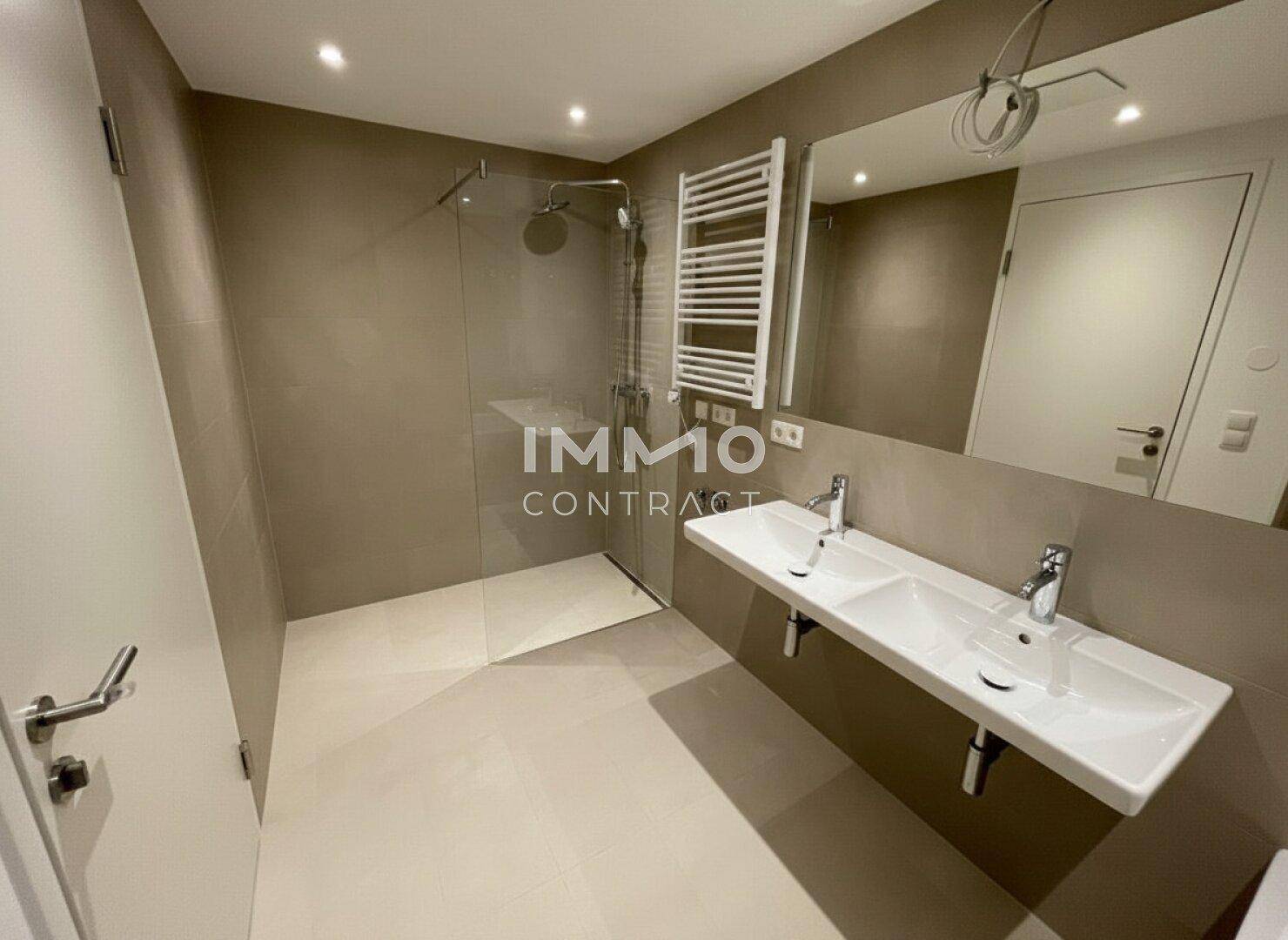 Modernes Badezimmer mit begehbarer Dusche, Doppelwaschbecken und beheiztem Handtuchhalter.