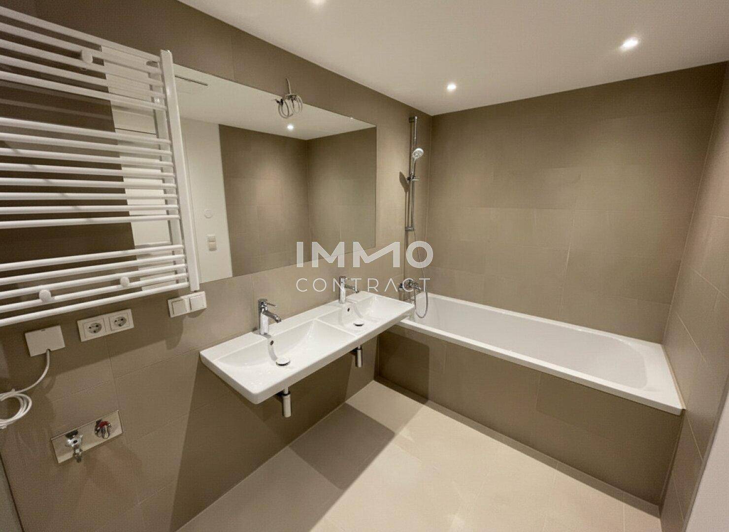 Modernes Badezimmer mit Badewanne, Doppelwaschbecken und praktischem Handtuchheizkörper.