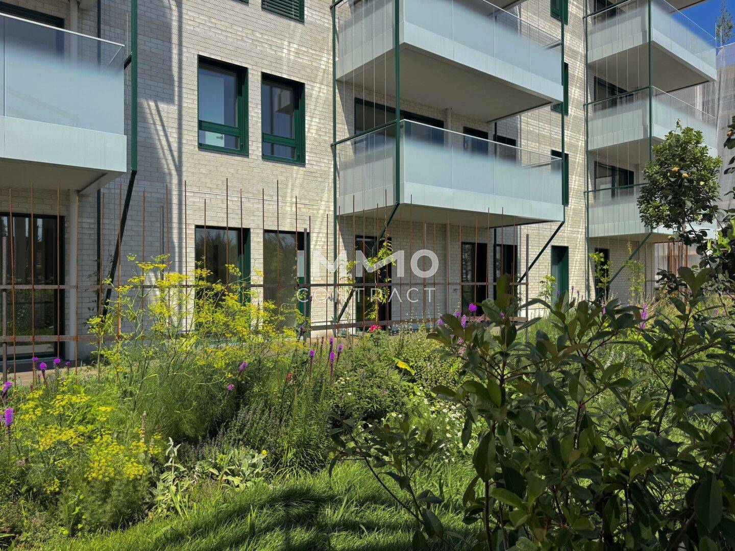 Moderne Wohnanlage mit mehreren Balkonen und einem gepflegten Gartenbereich im Vordergrund.