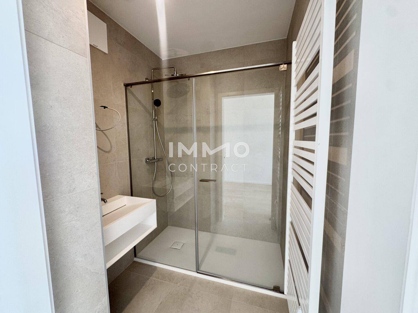 Modernes Badezimmer mit ebenerdiger Dusche, Wandfliesen und Handtuchheizkörper.