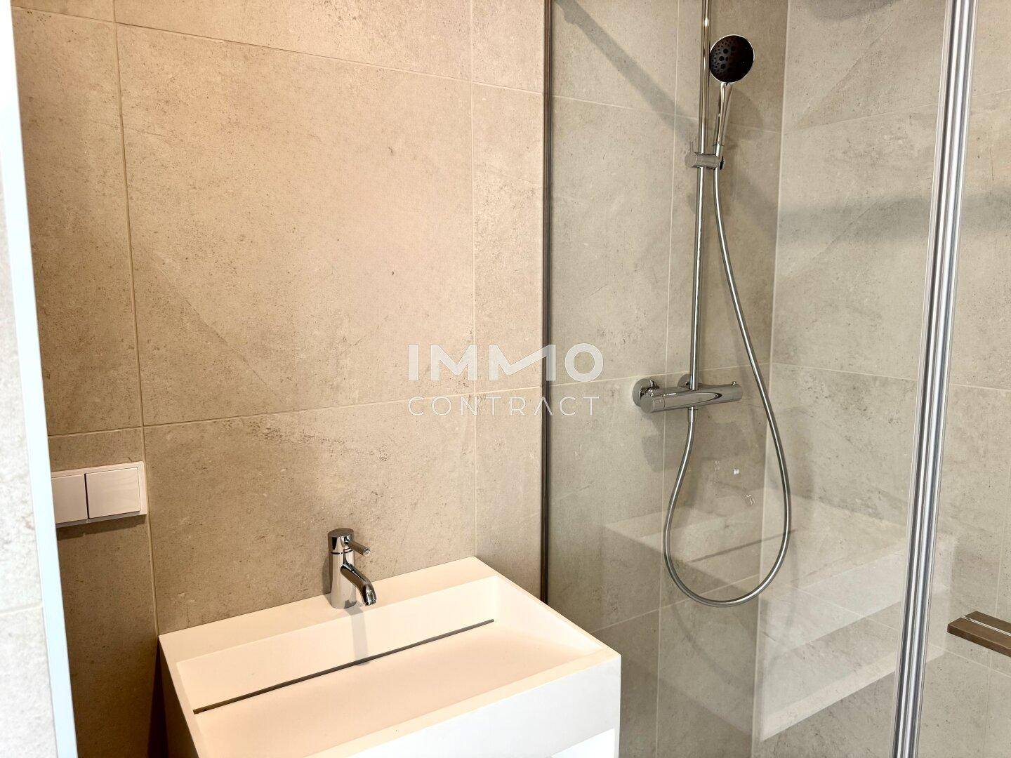 Modernes Badezimmer mit Duschbereich, Wandfliesen und minimalistischem Waschbecken.